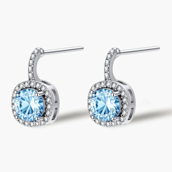 Sterling silver drop earrings featuring cushion-cut blue moissanite stones surrounded by sparkling halo settings
