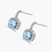 Sterling silver drop earrings featuring cushion-cut blue moissanite stones surrounded by sparkling halo settings