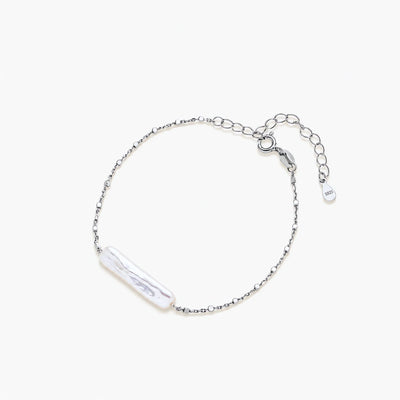 Minimalist bracelet with iridescent baroque pearl on rhodium-plated sterling silver chain against cream background